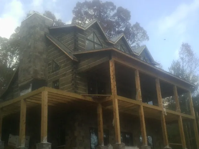 Stone chimney and dormers on a large log home with a timber porch in Buckeye