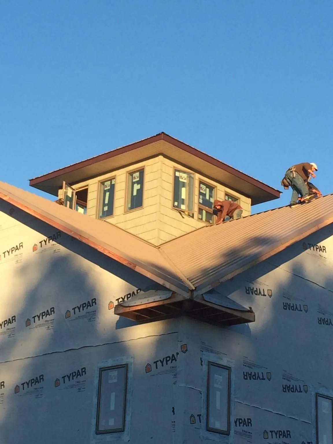 Roofers working around a rooftop cupola on a new metal roof at sunset — Roof Waterproofing in Buckeye by Roofing Brothers